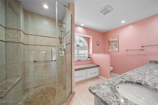 bathroom featuring tile patterned floors, vanity, toilet, and a shower with shower door