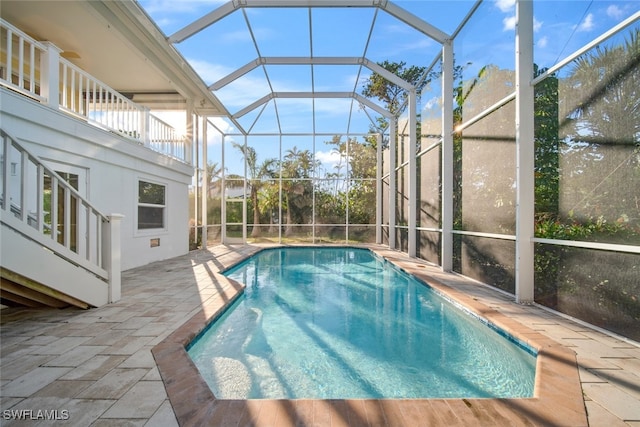 view of pool with glass enclosure and a patio area