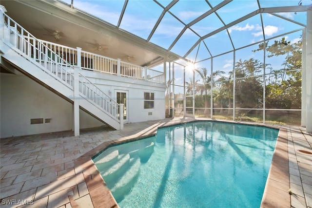 view of pool featuring a patio, glass enclosure, and ceiling fan