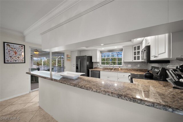 kitchen featuring dark stone countertops, white cabinetry, kitchen peninsula, and appliances with stainless steel finishes