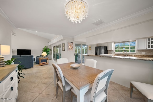 tiled dining space with crown molding, vaulted ceiling, and a notable chandelier