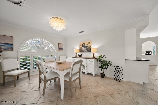 tiled dining space featuring ornamental molding and an inviting chandelier