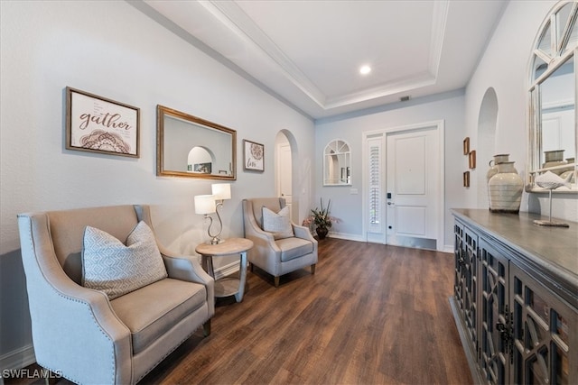 sitting room featuring dark wood-type flooring, ornamental molding, and a tray ceiling