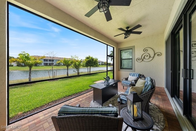 sunroom / solarium featuring ceiling fan and a water view