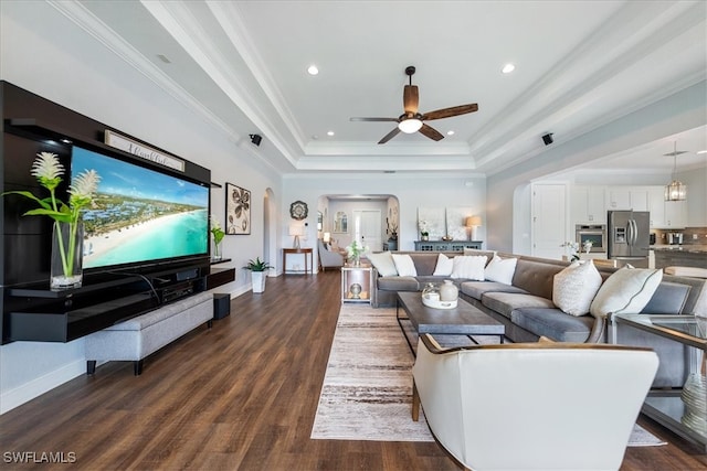 living room featuring hardwood / wood-style floors, ornamental molding, a raised ceiling, and ceiling fan