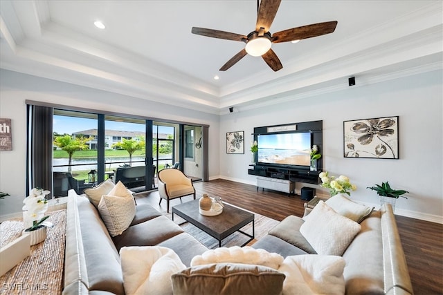 living room with hardwood / wood-style flooring, ceiling fan, a raised ceiling, and ornamental molding