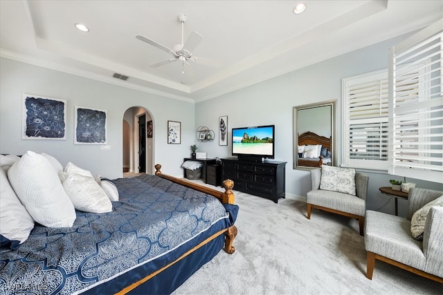 carpeted bedroom with crown molding, ceiling fan, and a tray ceiling