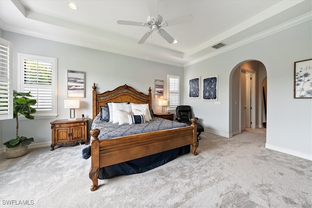 carpeted bedroom featuring multiple windows, ornamental molding, a raised ceiling, and ceiling fan