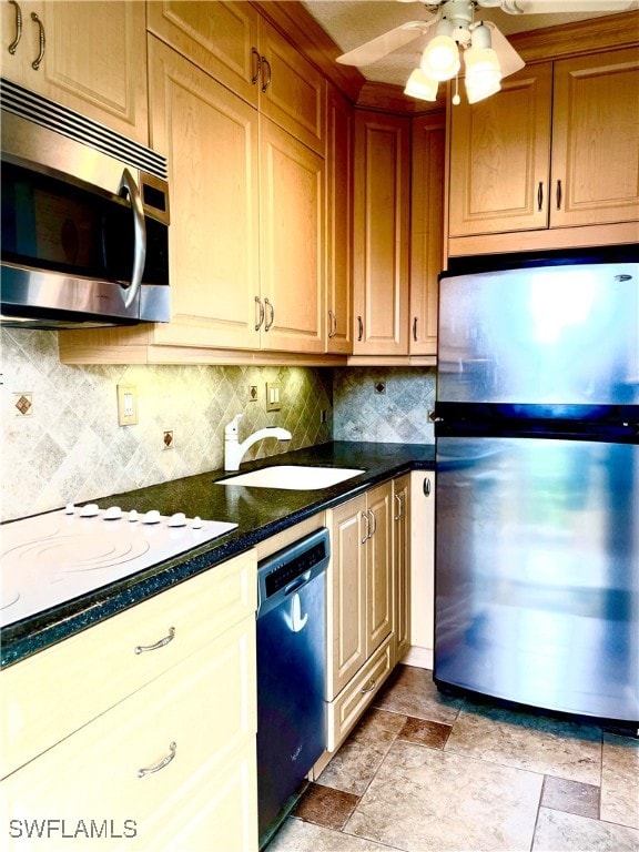 kitchen featuring ceiling fan, sink, stainless steel appliances, dark stone counters, and decorative backsplash