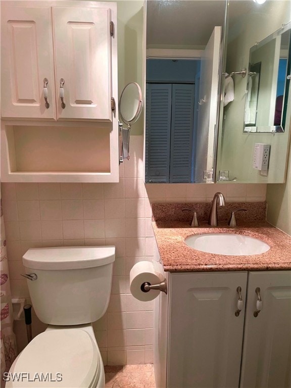 bathroom featuring tasteful backsplash, vanity, tile walls, and toilet