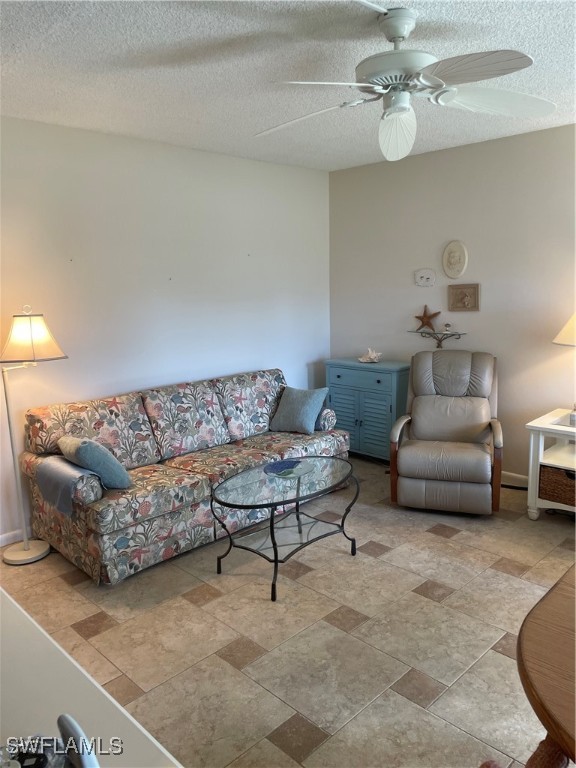 living room with a textured ceiling and ceiling fan