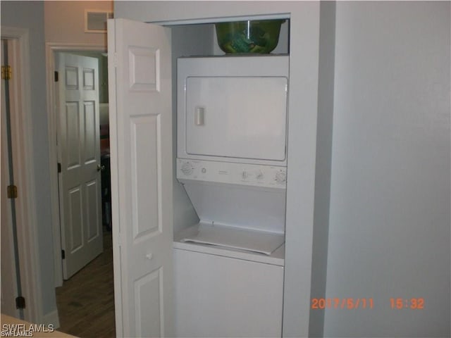 washroom featuring hardwood / wood-style flooring and stacked washer and dryer