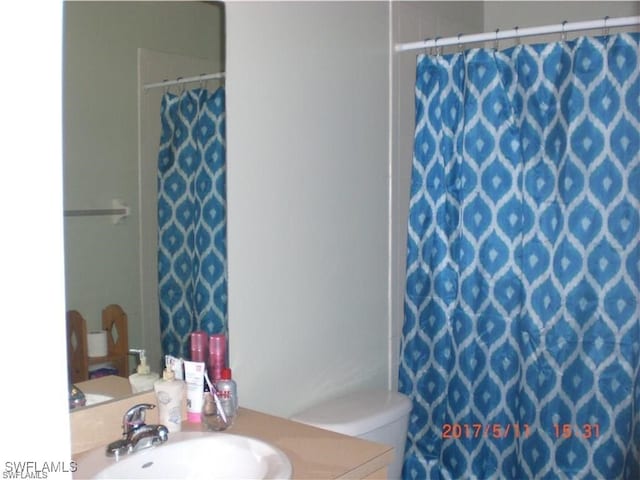 bathroom with curtained shower, toilet, and sink