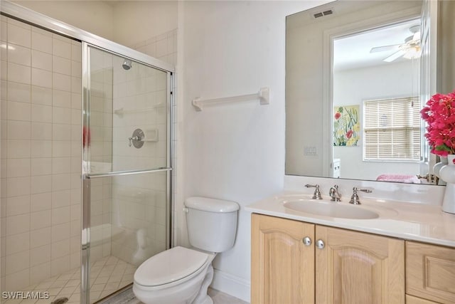 bathroom with ceiling fan, vanity, a shower with shower door, and toilet