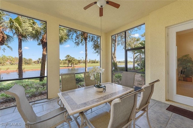 sunroom featuring ceiling fan and a water view