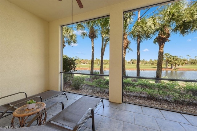 sunroom / solarium with ceiling fan, plenty of natural light, and a water view