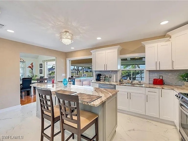 kitchen featuring decorative backsplash, sink, white cabinets, and a healthy amount of sunlight