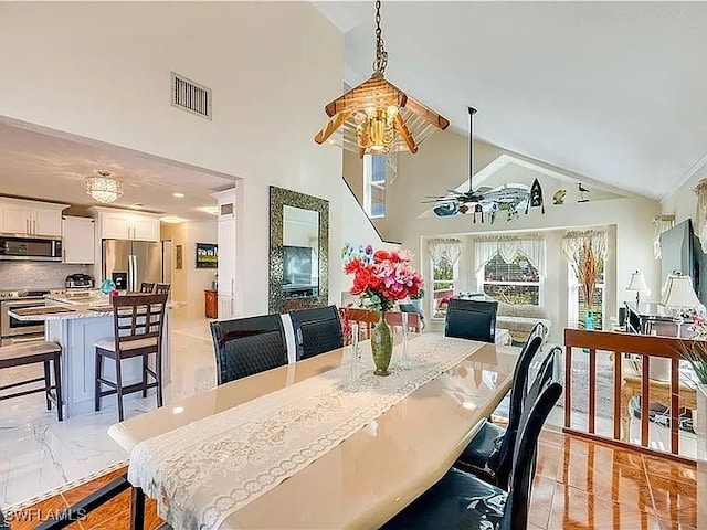 dining space with ceiling fan and high vaulted ceiling