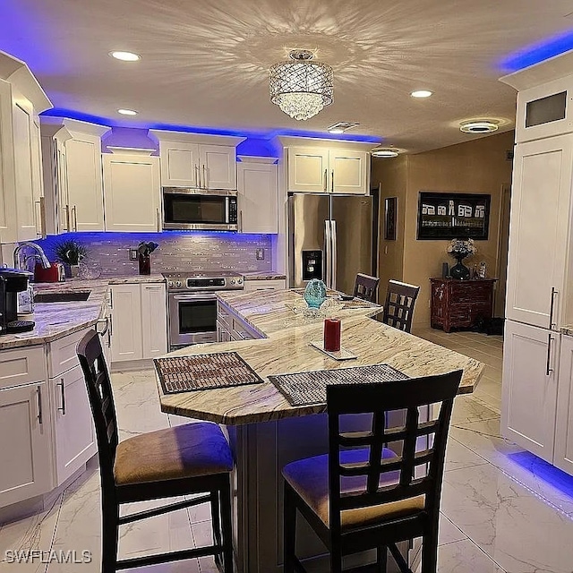 kitchen featuring white cabinetry, a center island, stainless steel appliances, an inviting chandelier, and a breakfast bar area