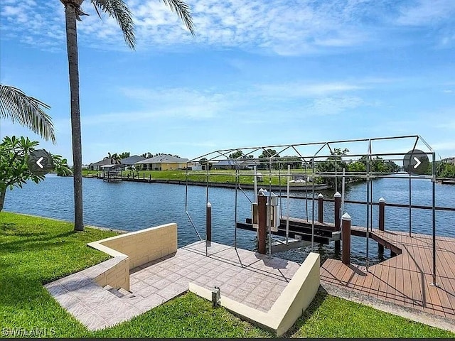 view of dock with a water view and a lawn