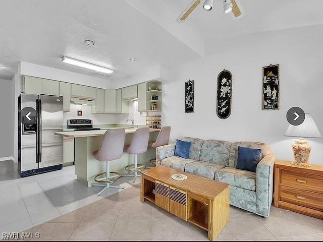 living room featuring light tile patterned floors, ceiling fan, and sink