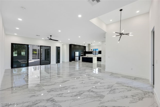 unfurnished living room with a high ceiling and ceiling fan with notable chandelier