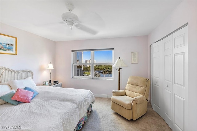 bedroom with ceiling fan, a closet, and light colored carpet