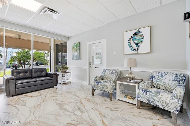 living room featuring a wainscoted wall, a paneled ceiling, and visible vents