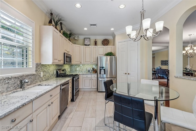 kitchen featuring stainless steel appliances, crown molding, sink, a notable chandelier, and hanging light fixtures