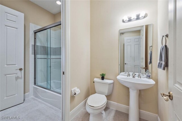 3189 Aviamar Cir Unit 202, Naples, FL 34114 - bathroom with toilet, tile patterned floors, shower / bath combination with glass door, baseboards, and a sink
