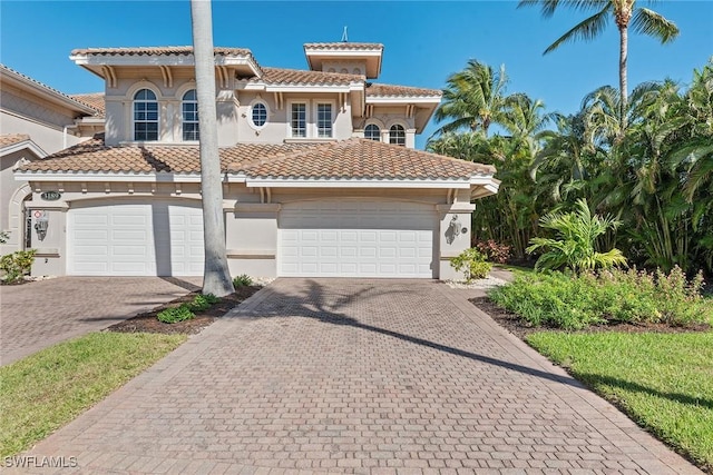 3189 Aviamar Cir Unit 202, Naples, FL 34114 - mediterranean / spanish home featuring a garage, a tiled roof, decorative driveway, stucco siding, and french doors