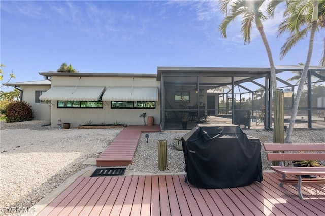 wooden deck featuring grilling area and glass enclosure