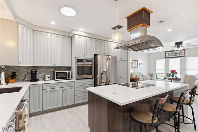 kitchen with appliances with stainless steel finishes, sink, backsplash, a kitchen bar, and hanging light fixtures