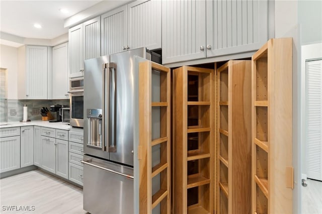 kitchen featuring gray cabinets, appliances with stainless steel finishes, backsplash, and light hardwood / wood-style flooring