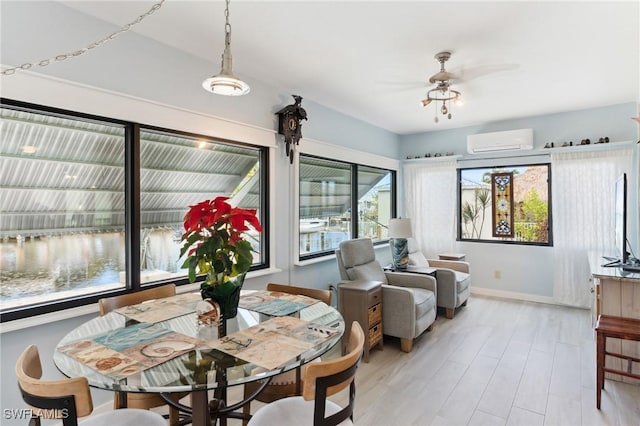 dining space featuring ceiling fan, plenty of natural light, light wood-type flooring, and an AC wall unit