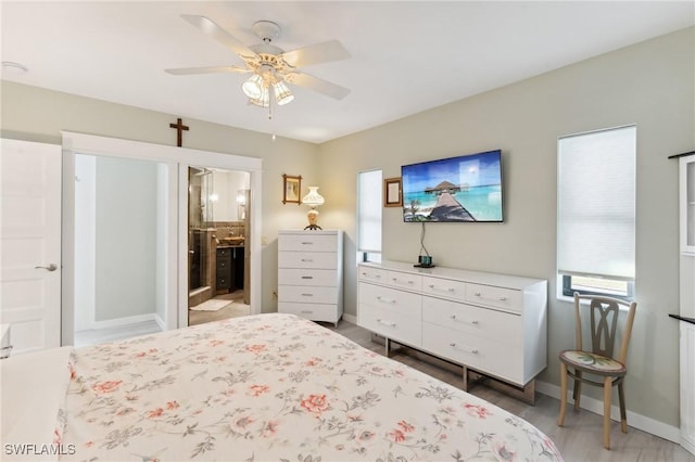 bedroom with multiple windows, ensuite bath, ceiling fan, and hardwood / wood-style flooring