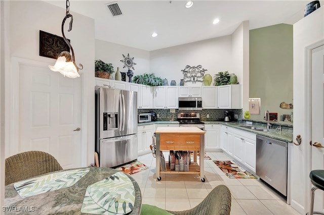 kitchen featuring tasteful backsplash, stainless steel appliances, sink, light tile patterned floors, and white cabinets