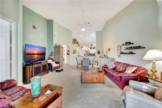 carpeted living room featuring high vaulted ceiling and ceiling fan with notable chandelier