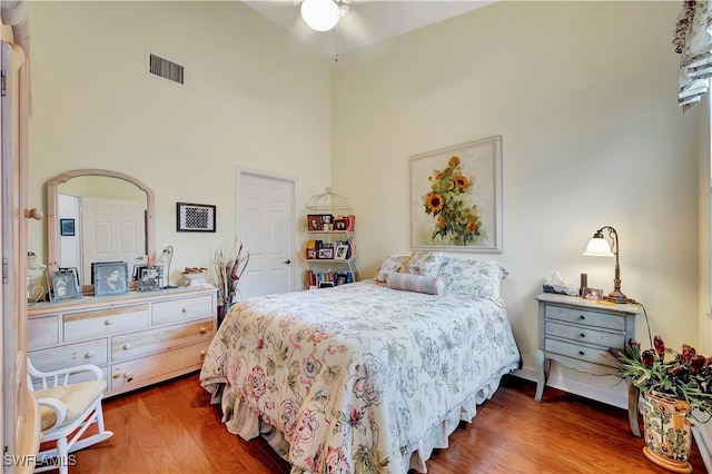 bedroom featuring wood-type flooring, a towering ceiling, and ceiling fan