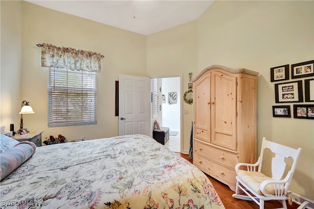 bedroom featuring wood-type flooring and a high ceiling