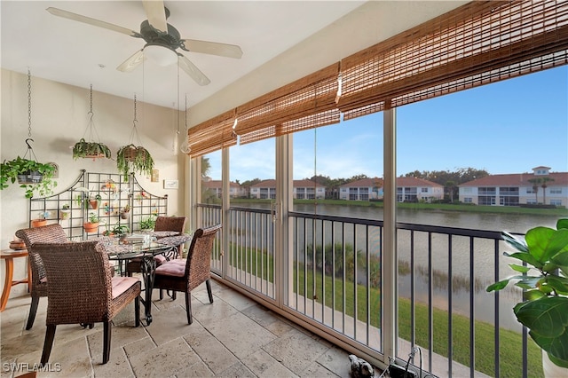 sunroom / solarium featuring a water view and ceiling fan