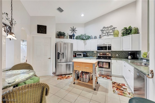 kitchen with tasteful backsplash, stainless steel appliances, high vaulted ceiling, white cabinets, and light tile patterned flooring