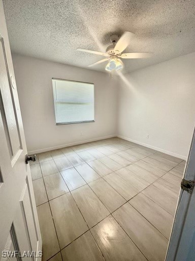 tiled spare room featuring ceiling fan and a textured ceiling