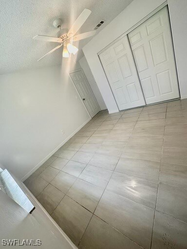 interior space with light tile patterned floors, a textured ceiling, a closet, and ceiling fan