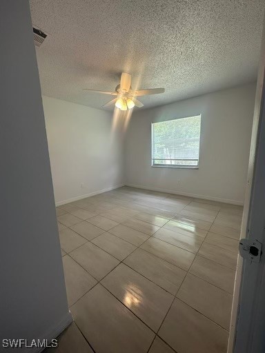 tiled empty room featuring ceiling fan and a textured ceiling