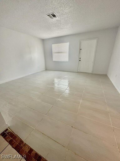 unfurnished room with light tile patterned floors and a textured ceiling