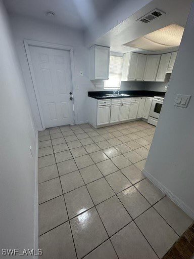 kitchen with white cabinets, white electric range, sink, and light tile patterned flooring