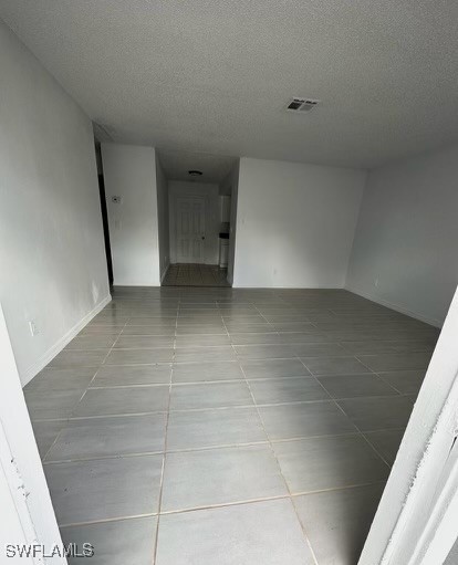 spare room featuring tile patterned floors and a textured ceiling