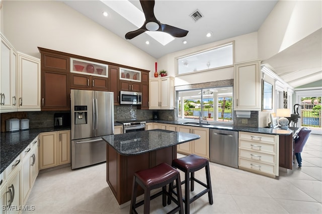 kitchen featuring appliances with stainless steel finishes, vaulted ceiling, a wealth of natural light, a breakfast bar, and a center island