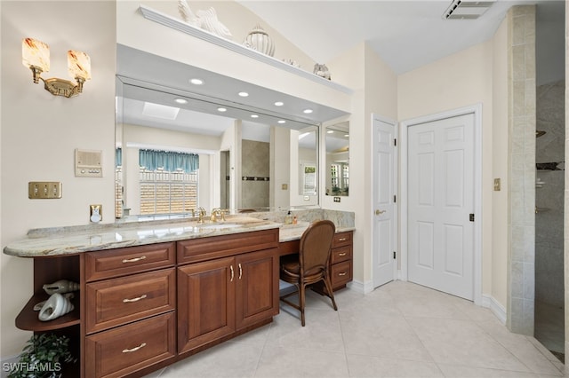 bathroom featuring vaulted ceiling, a tile shower, tile patterned floors, and vanity